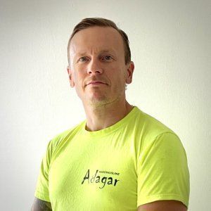 Neonkeltaiseen t-paitaan pukeutunut mies poseeraa yksinkertaista valkoista seinää vasten