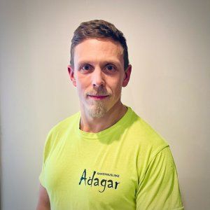 Neonkeltaiseen Adagar-t-paitaan pukeutunut mies poseeraa yksinkertaista seinää vasten