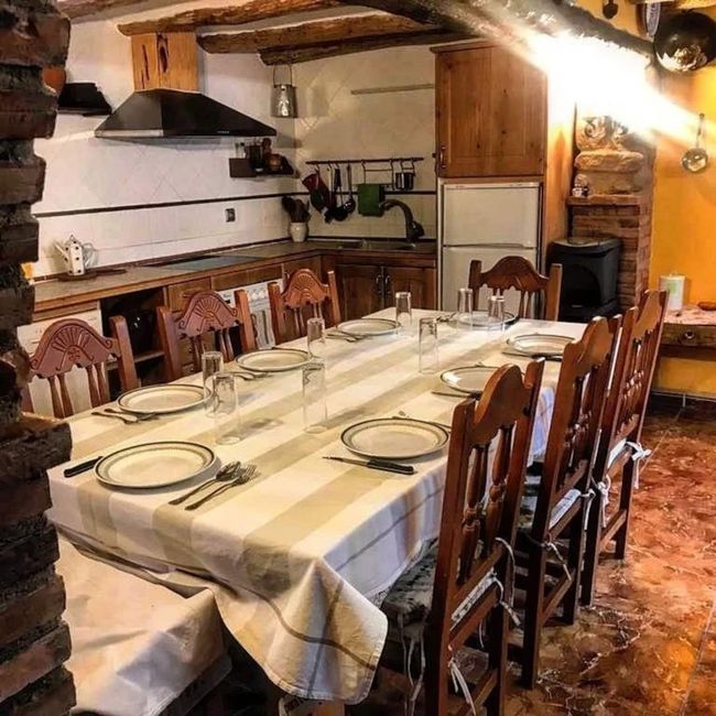 Una mesa larga con platos y vasos en una cocina.