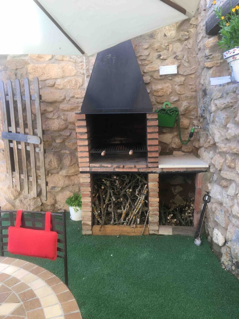 Una parrilla de barbacoa está construida en el costado de una pared de piedra.