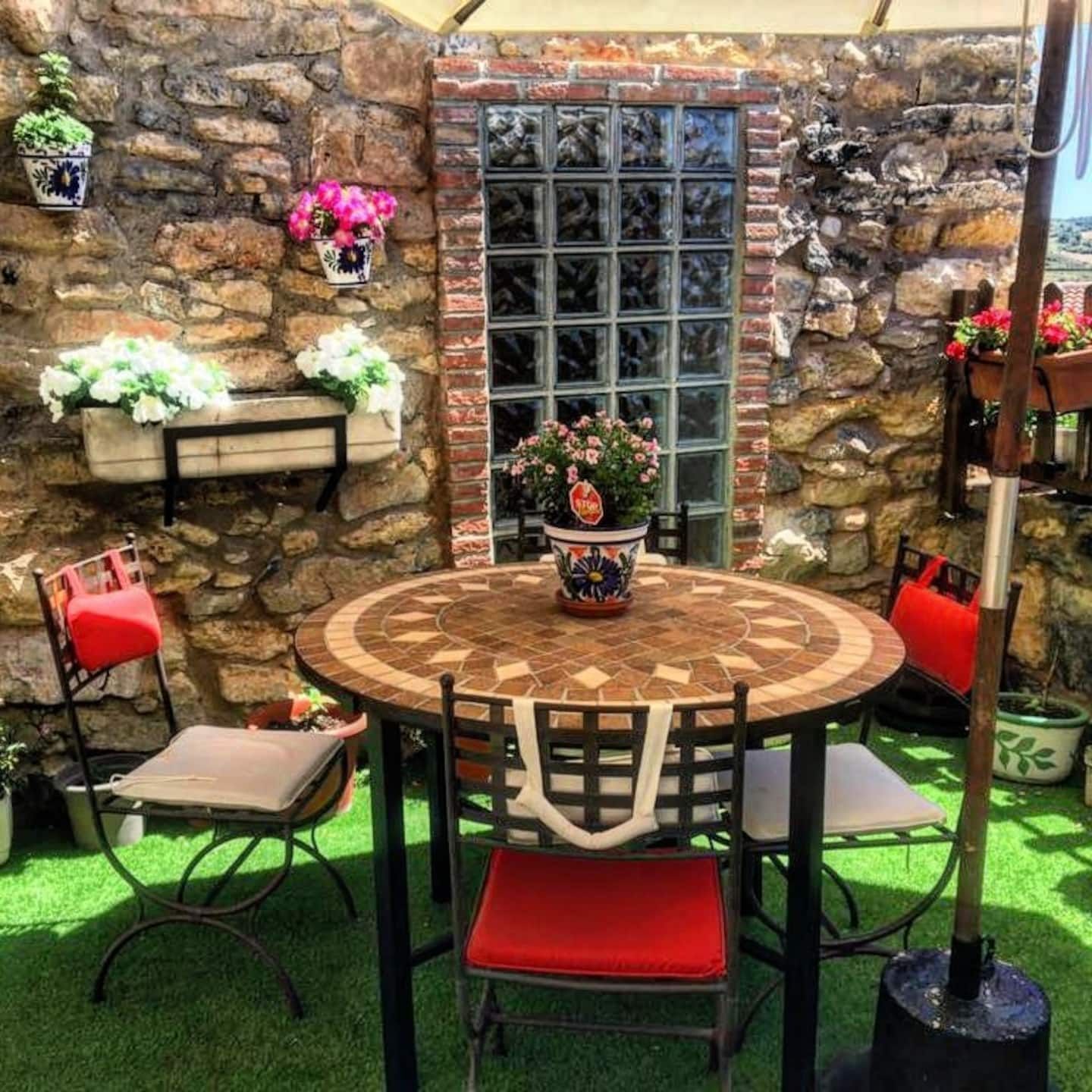 Un patio con una mesa y sillas frente a un muro de piedra.