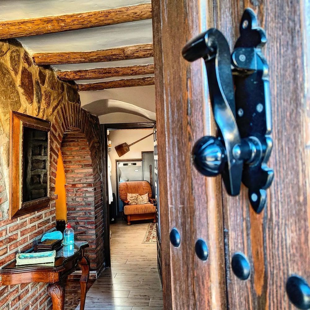 Una puerta de madera con una manija negra y una pared de ladrillos detrás de ella.