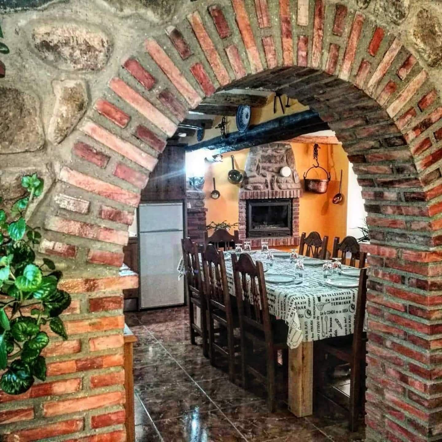 Un arco de ladrillo conduce a un comedor con mesa y sillas.