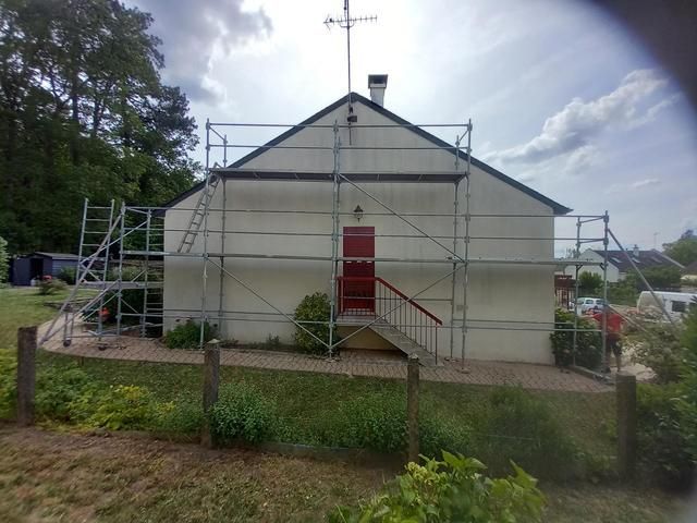 Des échafaudages devant une maison à la porte rouge