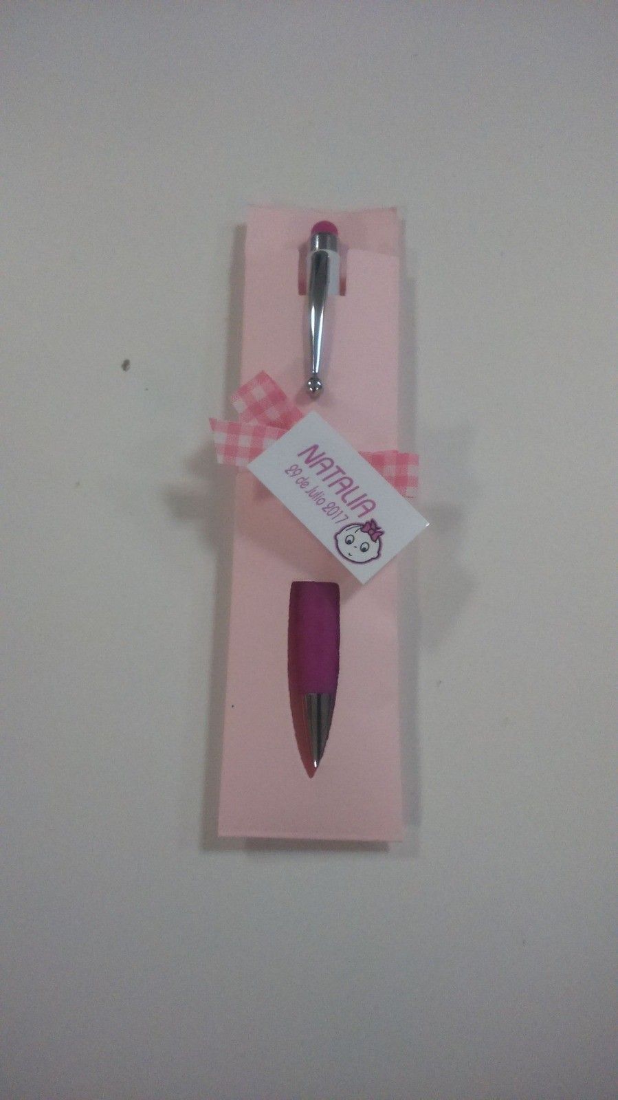 Bolígrafo rosa en un tarjetero rosa, atado con una cinta rosa y una pequeña etiqueta.