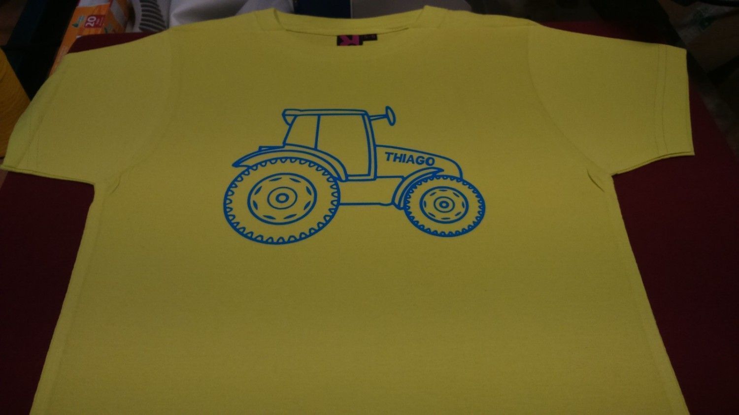 Camiseta amarilla con contorno azul de un tractor.