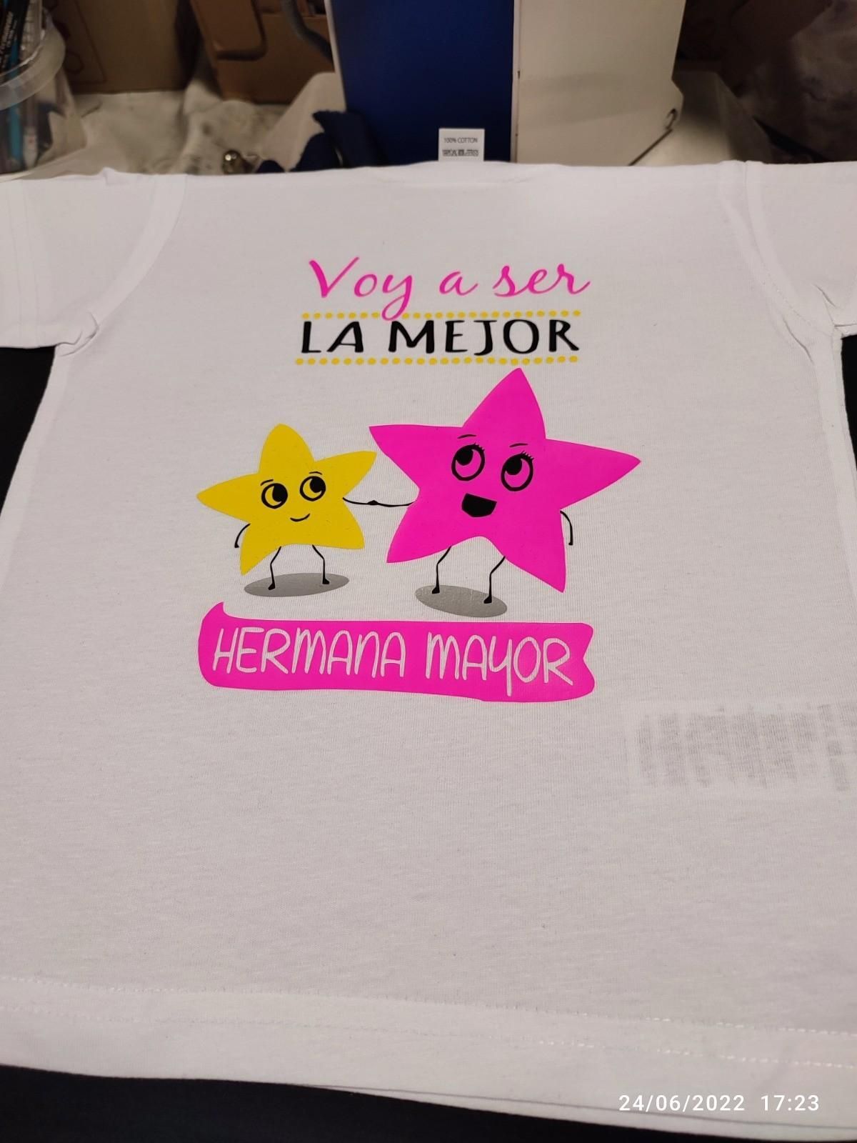 Camiseta blanca con gráficos de estrellas rosas y amarillas, el texto dice 