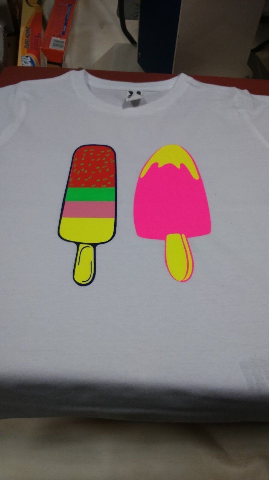 Camiseta blanca con dos diseños de paletas de colores: uno en capas y otro rosa sólido.