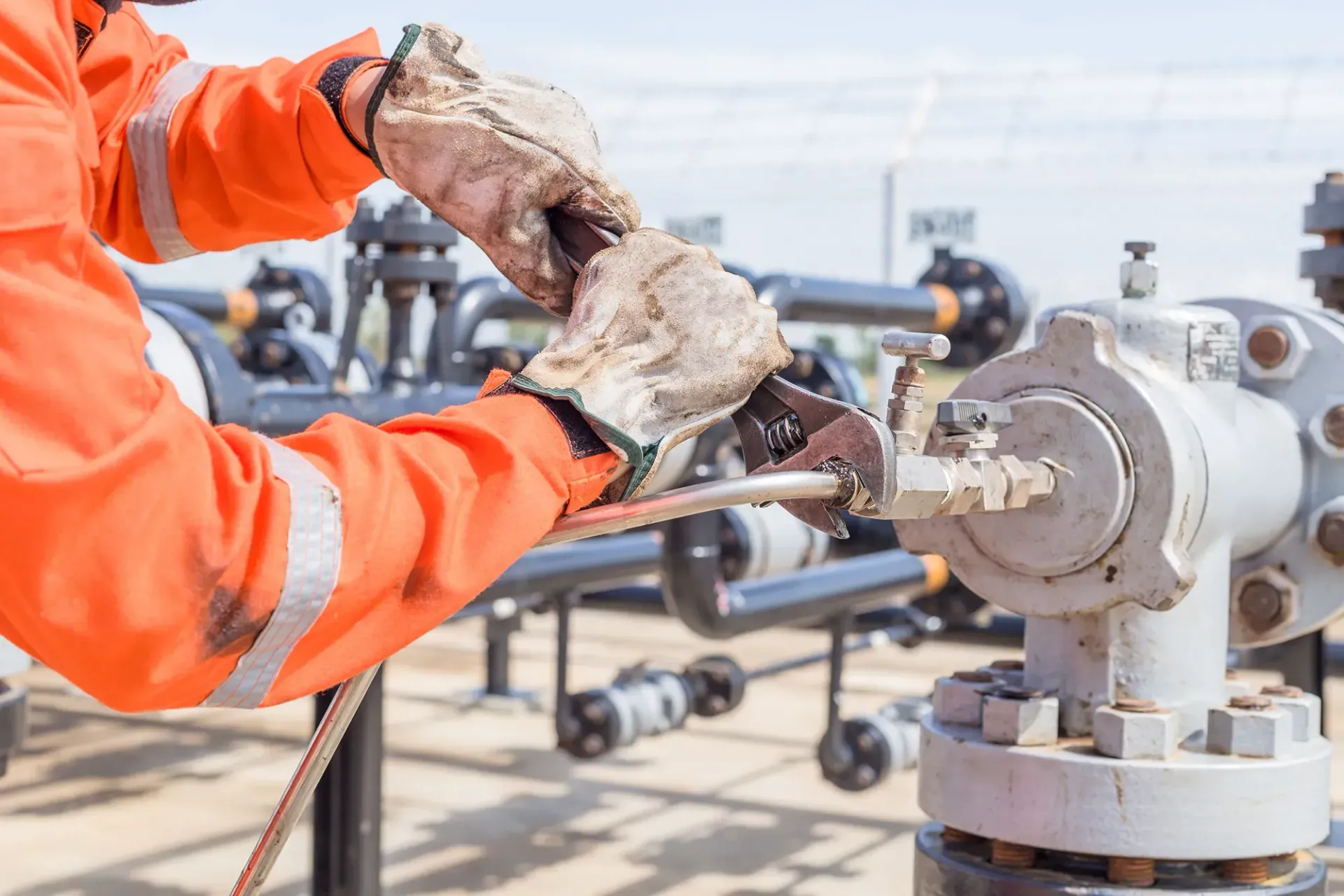 Ein Mann in einer orangefarbenen Jacke arbeitet an einem Rohr.