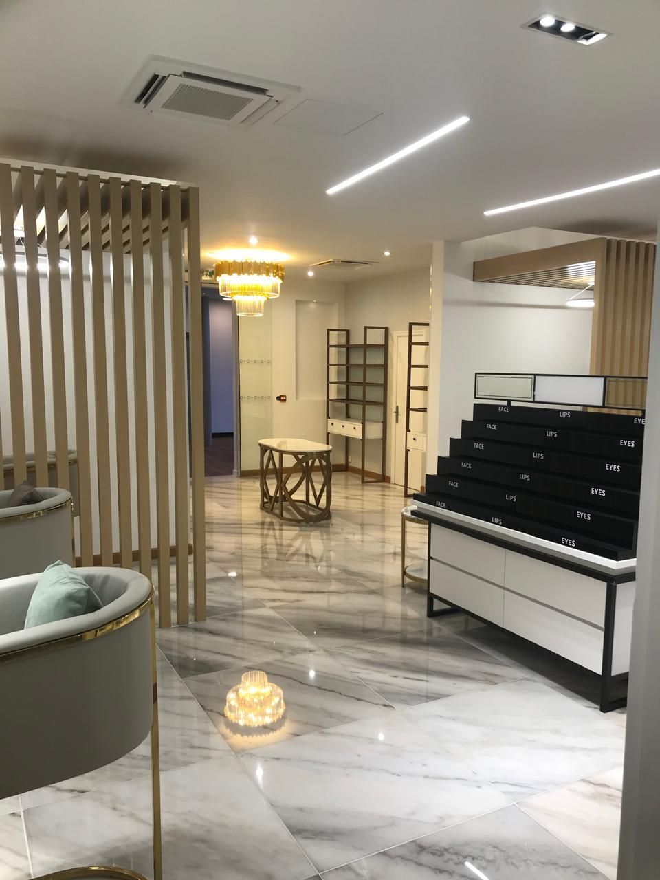 Intérieur vide d'une bijouterie avec sol en marbre, vitrines et luminaire décoratif.