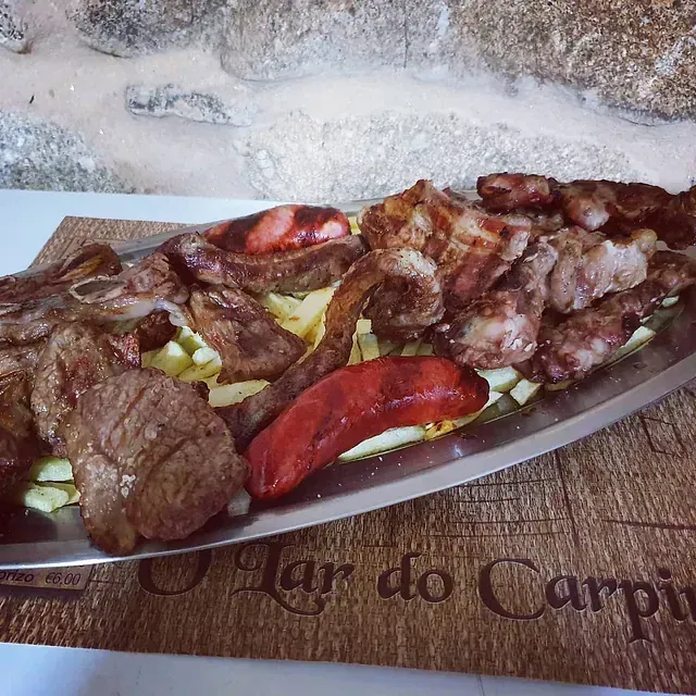 Un plato de carne y verduras reposa sobre un mantel que dice mar do carpio