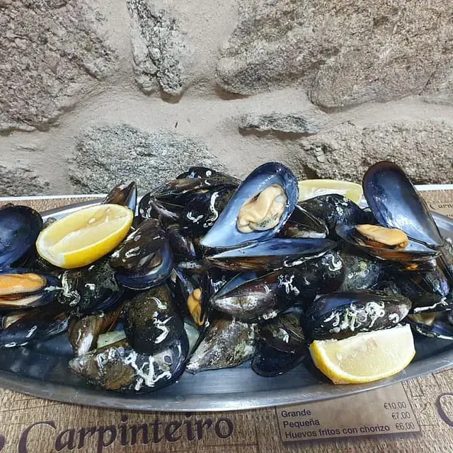 Un plato de mejillones con rodajas de limón sobre una mesa.