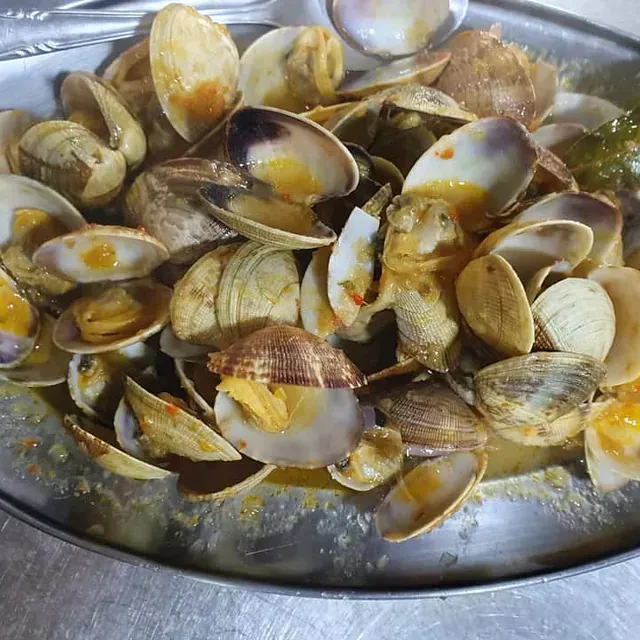 Un plato de almejas con una cuchara dentro