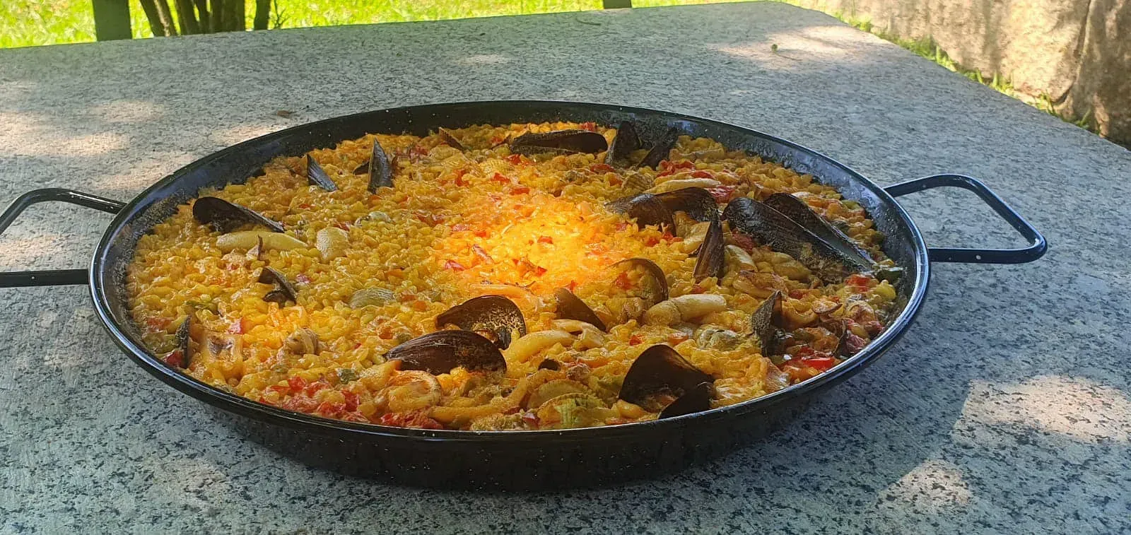Una sartén con comida está sobre una mesa afuera