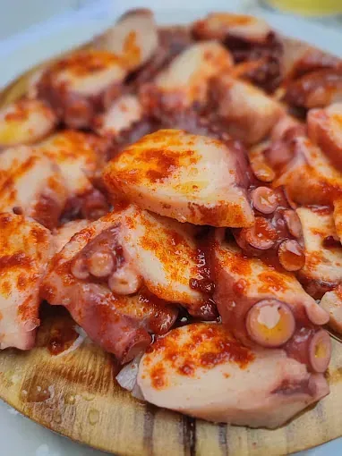 Un primer plano de un plato de pulpo sobre una tabla de cortar de madera.