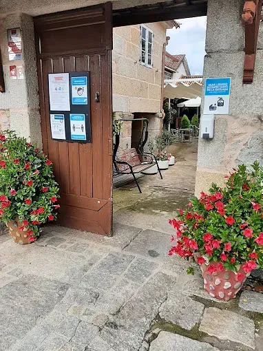 Una puerta de madera se abre a un edificio de piedra con flores delante de él.