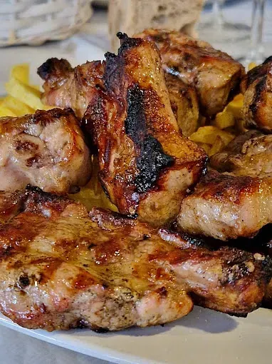 Un plato blanco cubierto con pollo a la parrilla y papas fritas.