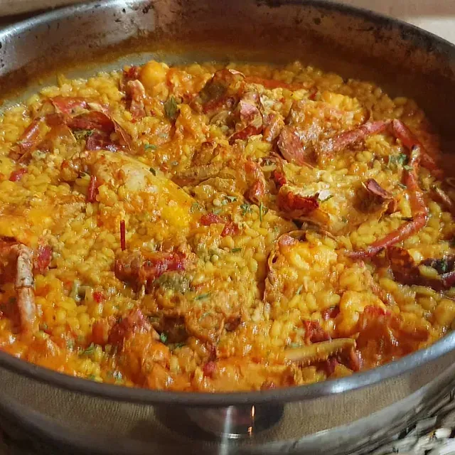 Una sartén llena de arroz, carne y verduras está sobre una mesa.