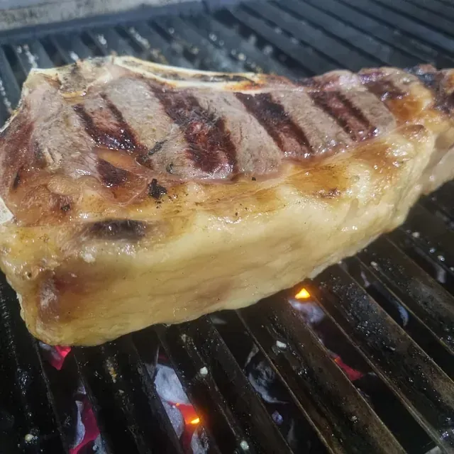 Un gran trozo de carne se está cocinando en una parrilla.
