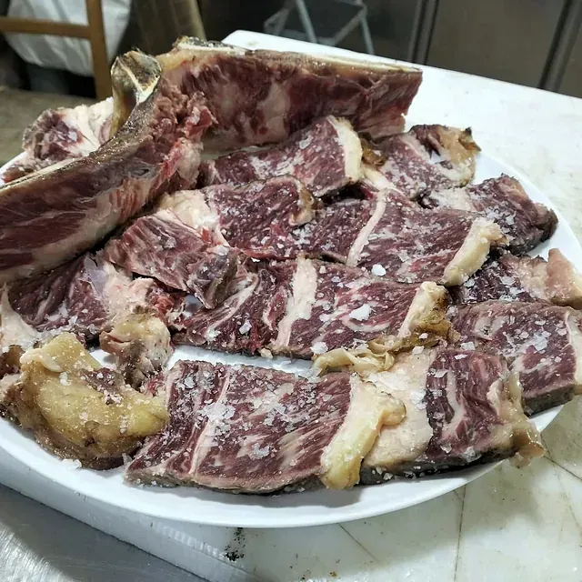 Un plato blanco lleno de carne y huesos sobre una mesa.