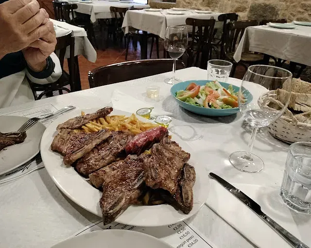 Un plato de carne y patatas fritas en una mesa de un restaurante.