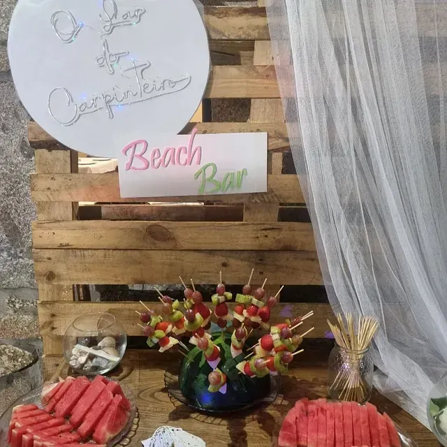 Una mesa con brochetas de sandía y un cartel que dice bar de playa
