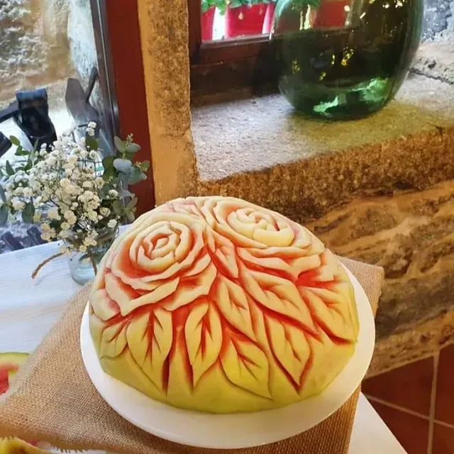 Una sandía con hojas y rosas talladas en ella.