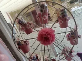 Una noria decorada con macetas y flores rosas se encuentra frente a una ventana.
