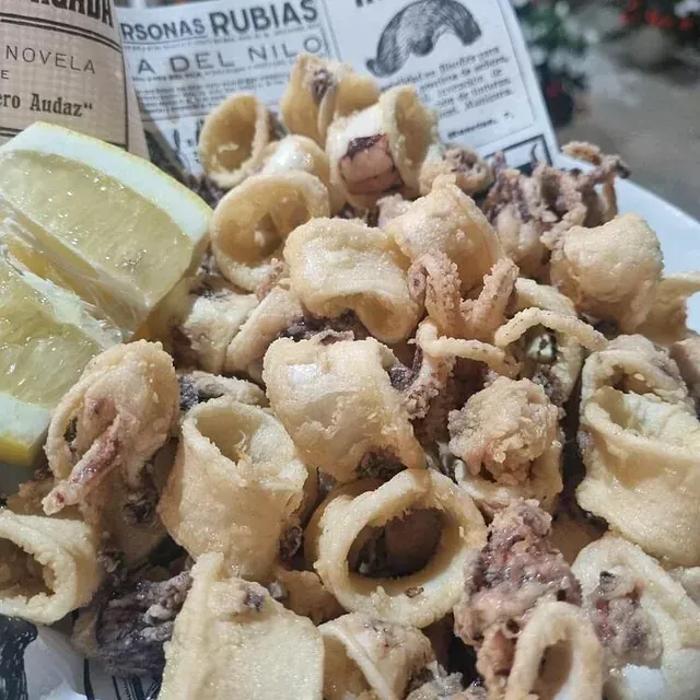 Un plato de calamares fritos con una rodaja de limón