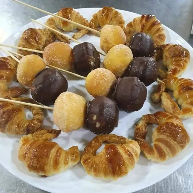 Un plato blanco cubierto con croissants y bolas de chocolate.