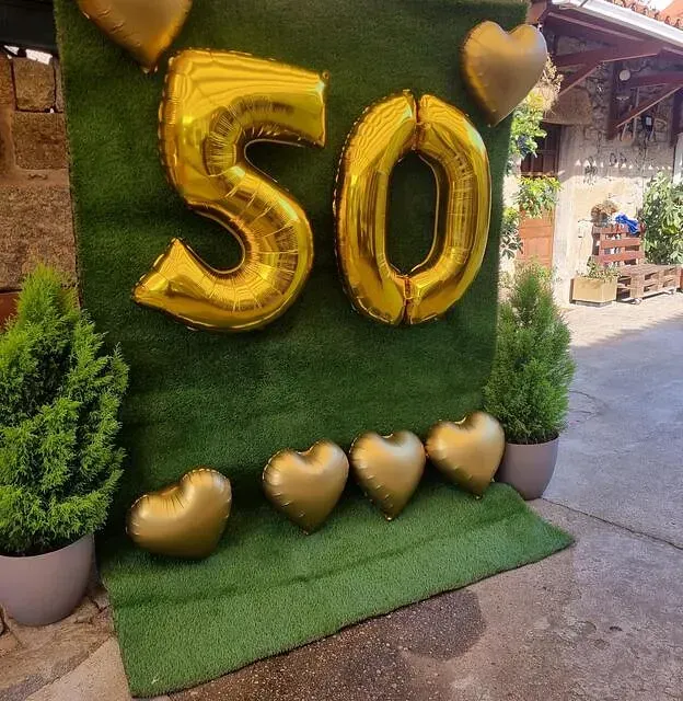 Una pared verde con globos en forma del número 50