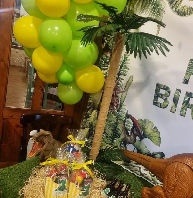 Una decoración de cumpleaños con globos y un dinosaurio.