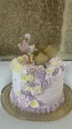 En un plato hay un pastel con flores y una cigüeña encima.