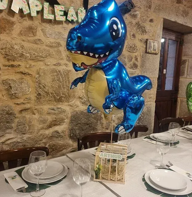 Un globo azul con forma de dinosaurio está sobre una mesa.