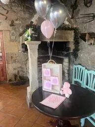 Una mesa con globos y un osito de peluche encima en una habitación.
