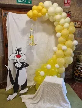 El gato Silvestre está parado frente a un arco de globos.