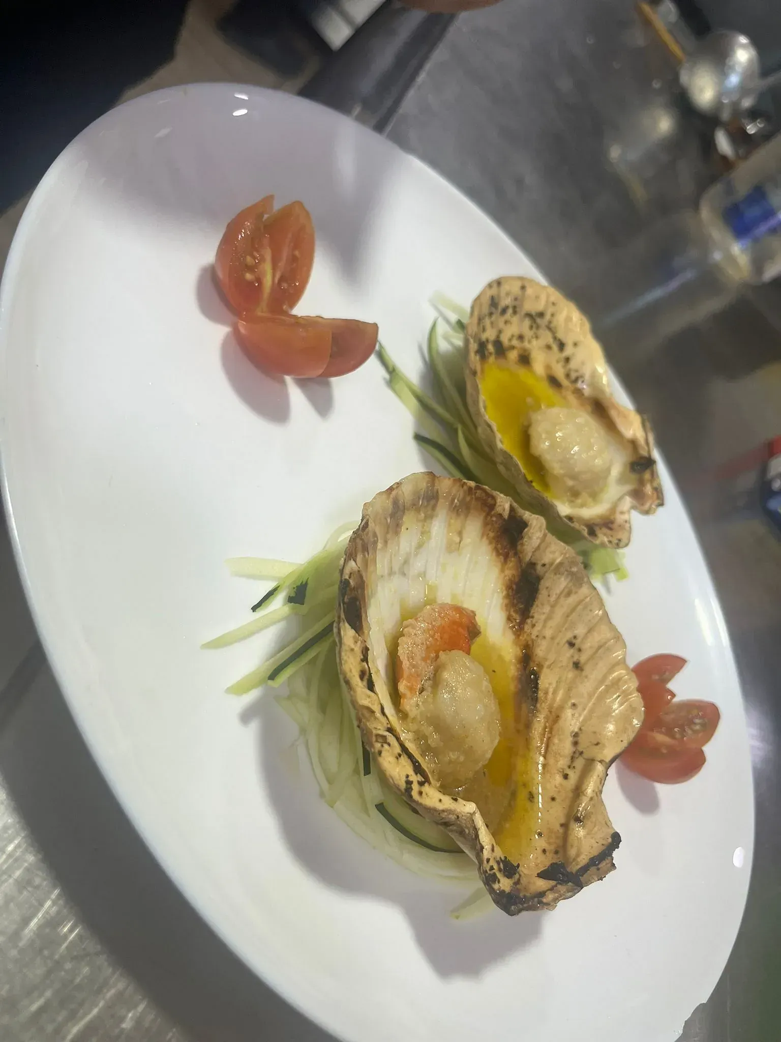 Un plato blanco cubierto de ostras y tomates sobre una mesa.