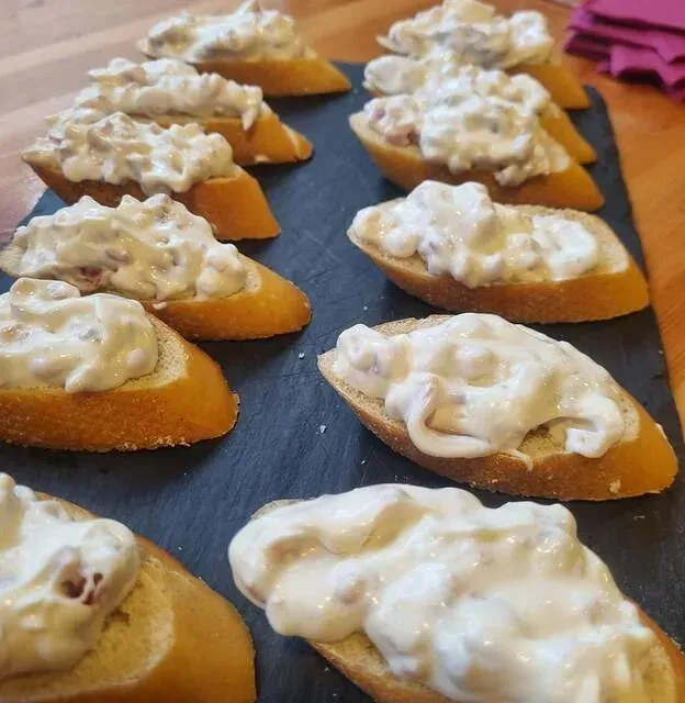 Un montón de rebanadas de pan con salsa blanca encima.