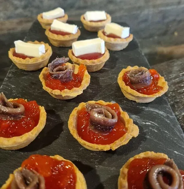 Una bandeja de aperitivos con salsa de tomate y anchoas