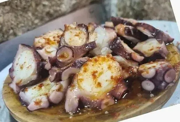 Un plato de pulpo sobre una tabla de cortar de madera