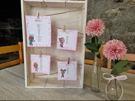 Una mesa con un jarrón de flores rosas y tarjetas encima.