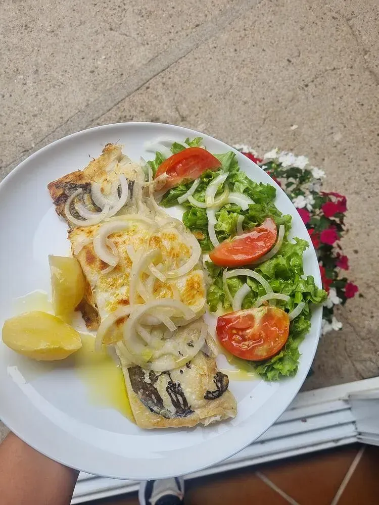 Una persona sostiene un plato de comida con patatas y verduras.