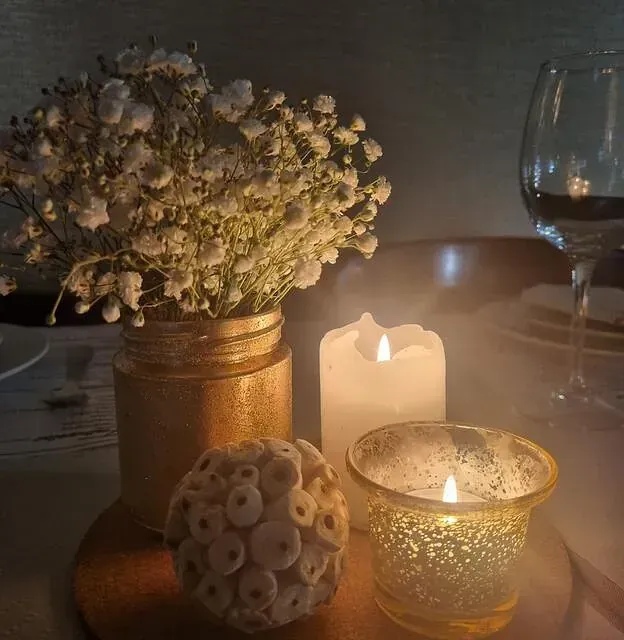 Velas y flores en una mesa con una copa de vino.