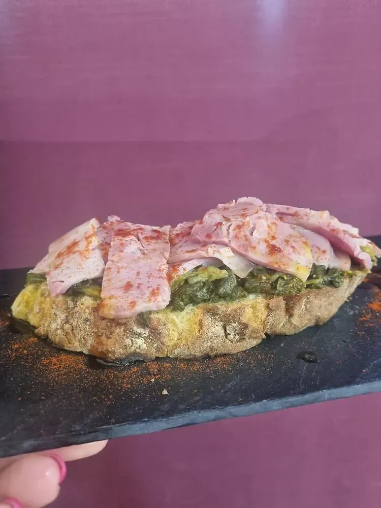 Una persona sostiene un sándwich en un plato negro.