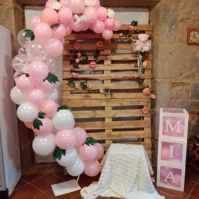 Una paleta de madera con globos rosas y blancos encima.