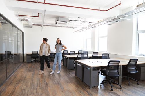 Un hombre y una mujer están de pie en una oficina hablando entre sí.