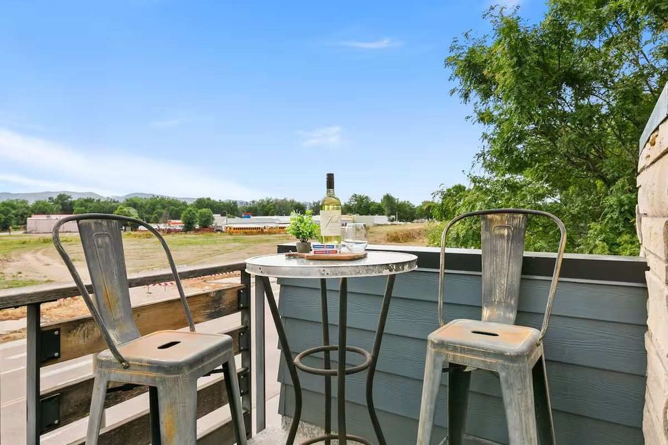 Patio bar with two stools, round table, and desert landscape under a blue sky