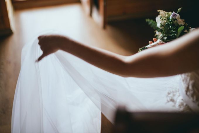 Una persona sostiene una tela blanca transparente cerca de un ramo de flores bajo una luz tenue de interior.