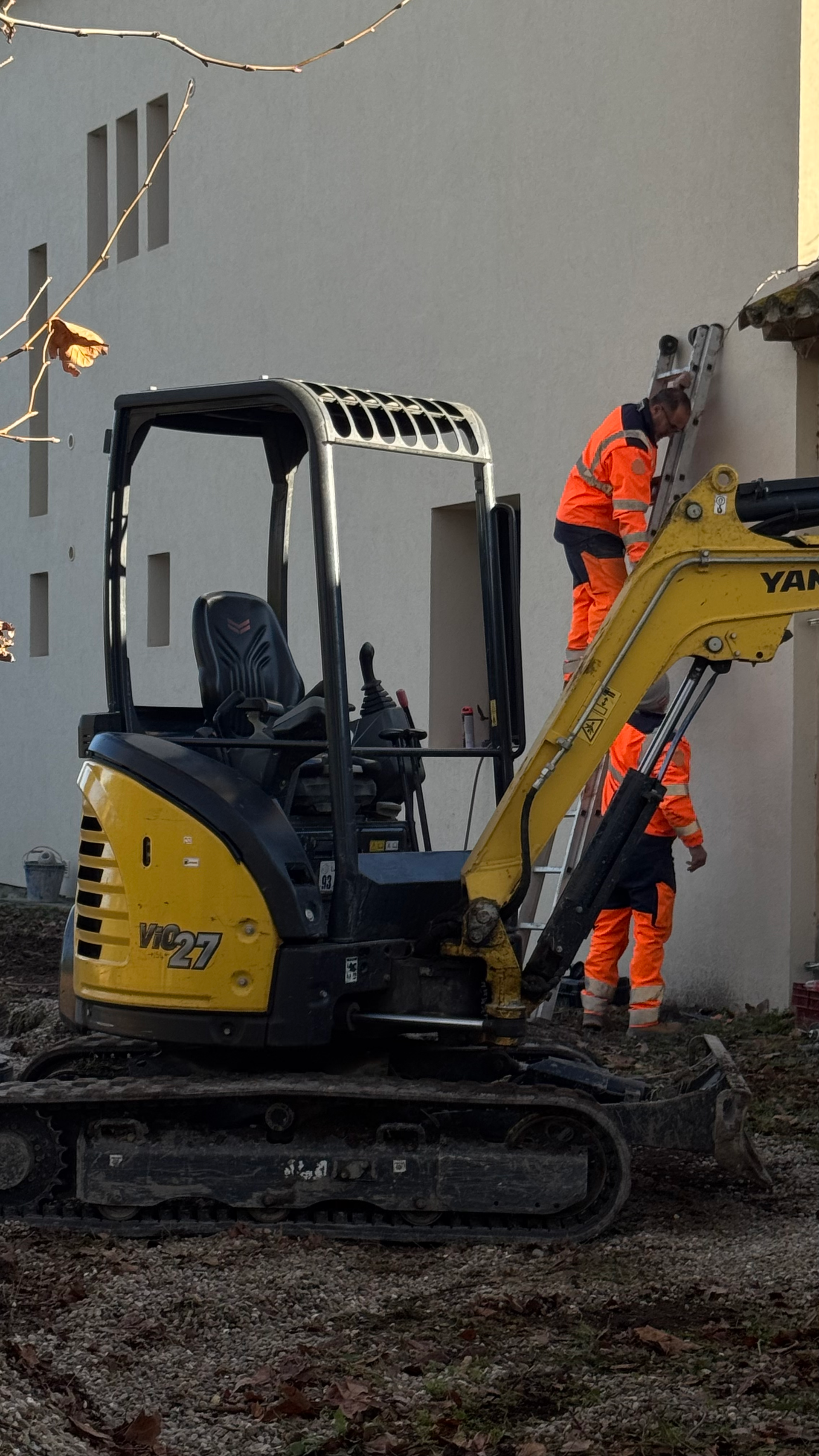 Techniciens en intervention sur une façade, accompagnés d’une mini-pelle Yanmar sur un chantier de terrassement et d’aménagement.
