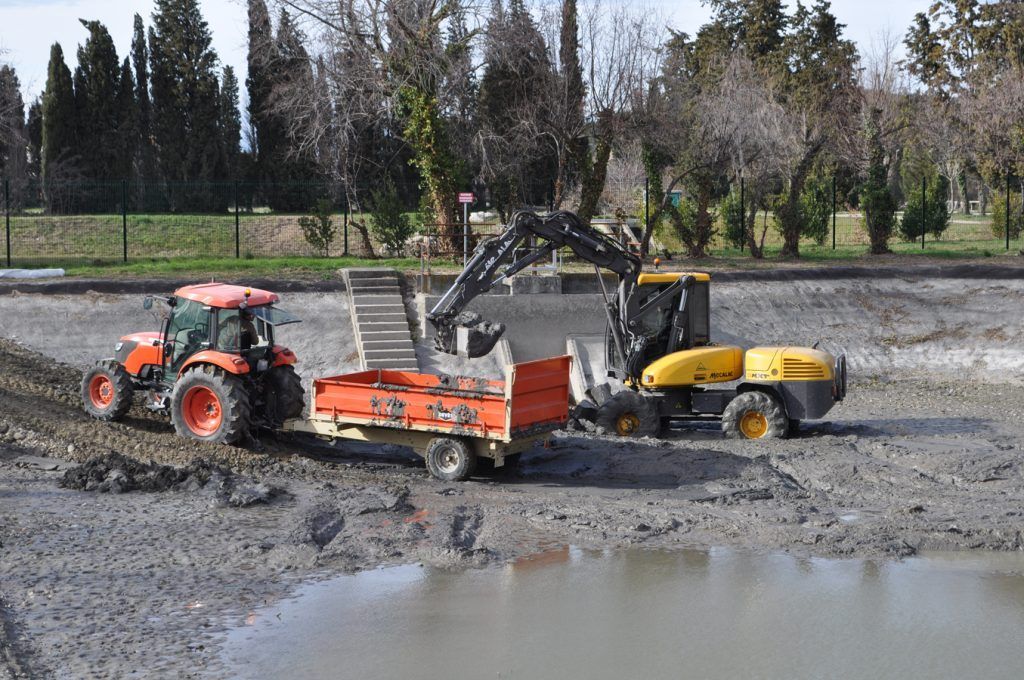 Tractopelle chargeant une petite benne accrochée à un tracteur